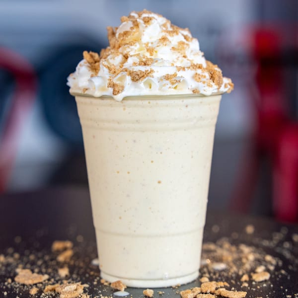 A Smashers milkshake topped with whipped cream and crushed graham crackers on a dark surface.